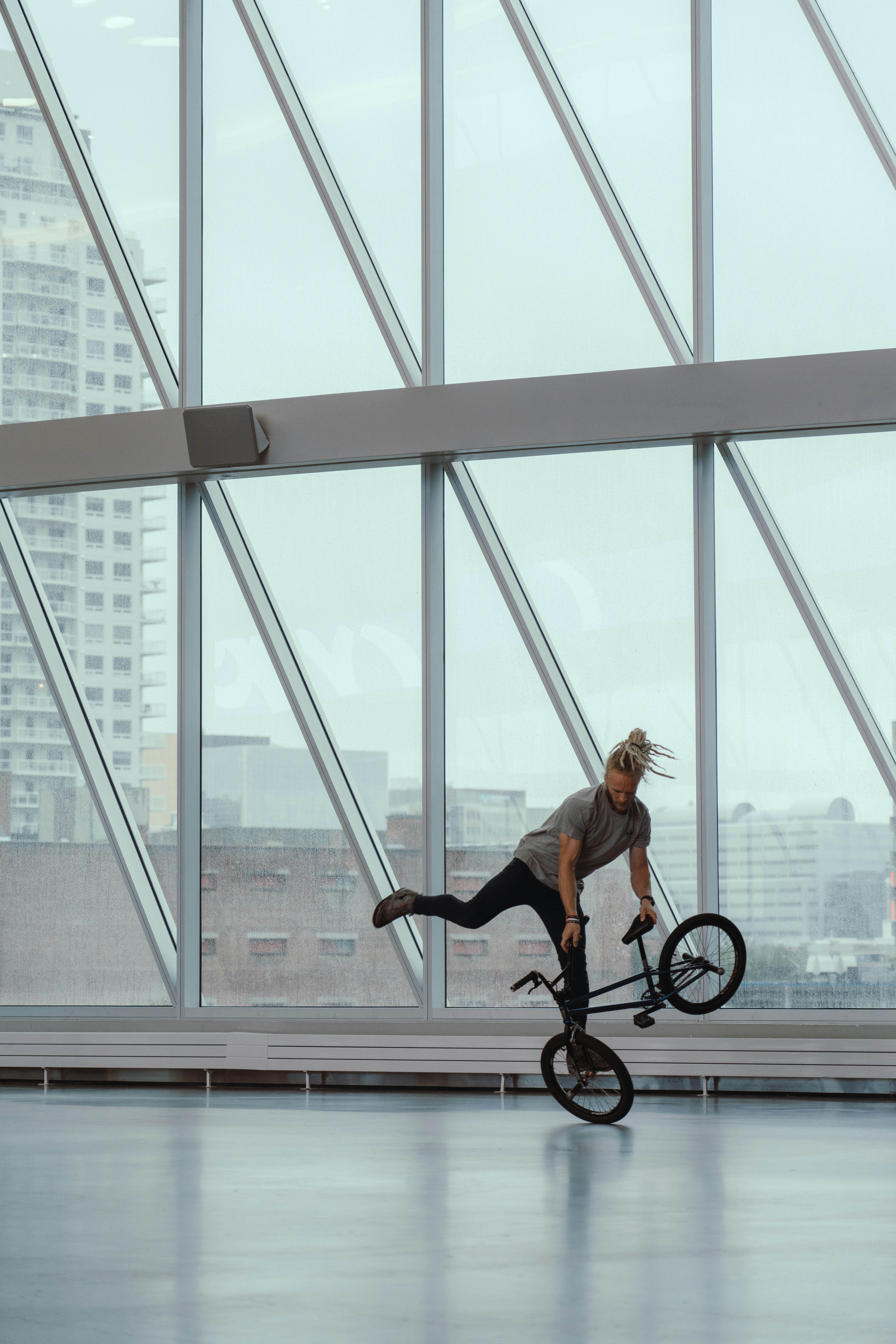 man riding bicycle doing stunts inside glass building during daytime