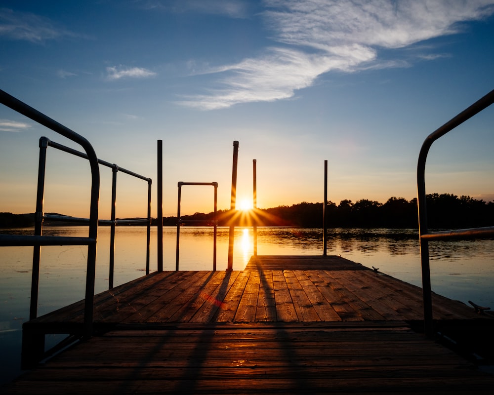 brown wooden dock on body of water during sunset
