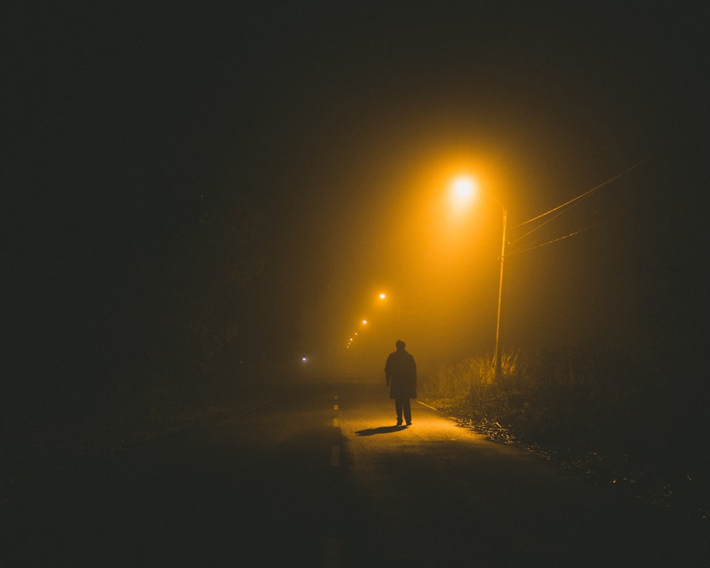 persona che cammina sul ciglio della strada di notte