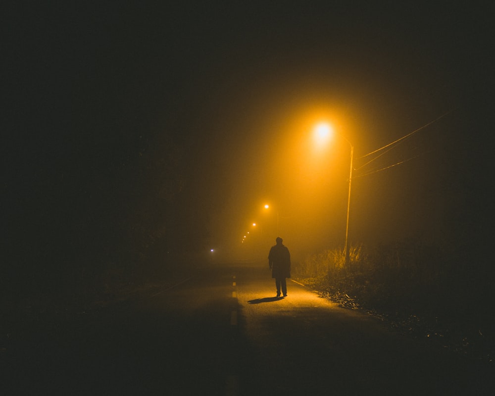 person walking on road side at night time