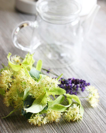 A peaceful scene of a clay teapot surrounded by fresh flowers and a linen cloth.
