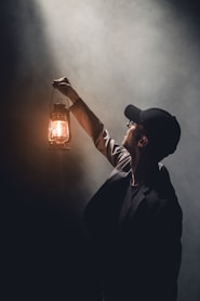 man holding lighted gas lantern