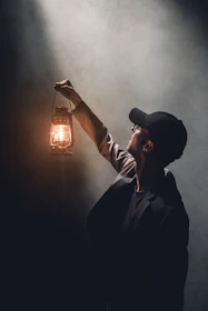 man holding lighted gas lantern
