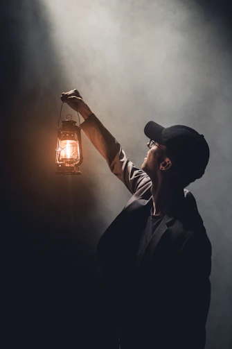 man holding lighted gas lantern