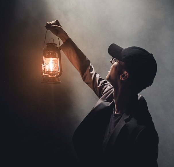 man holding lighted gas lantern