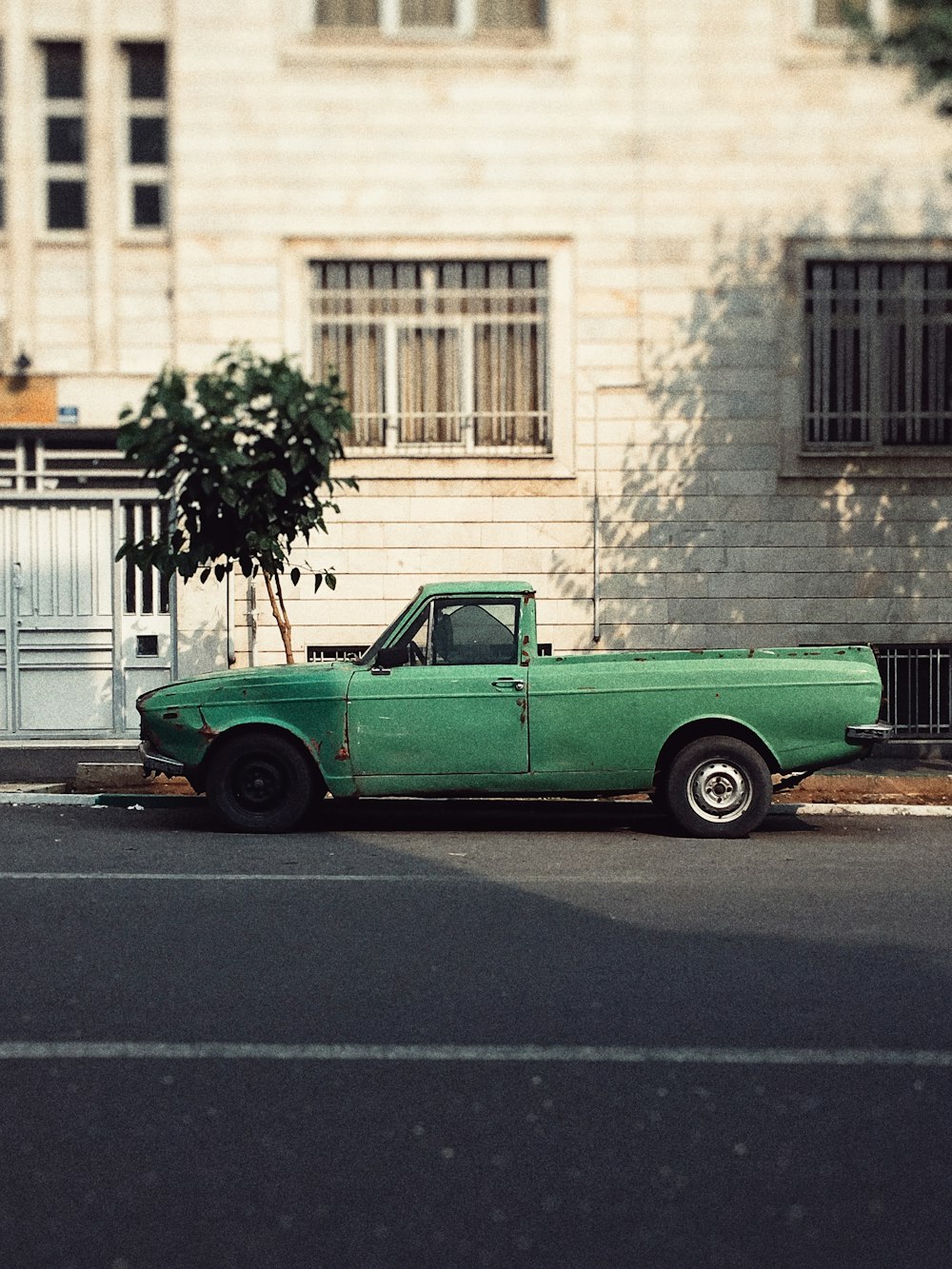 Camioneta verde de cabina simple estacionada al lado del edificio