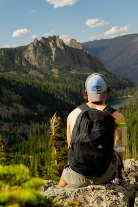 man sitting on stone looking at mountain