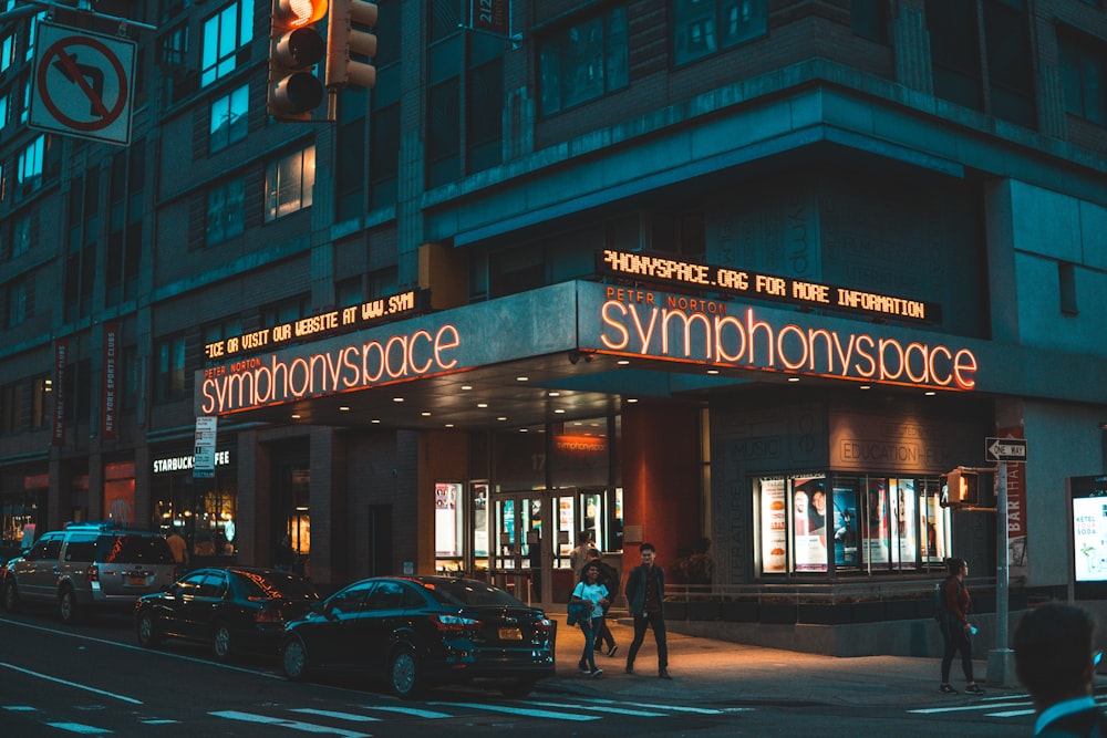 personnes marchant à côté du magasin Symphony Space pendant la nuit