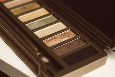 Close-up of a luxurious pink and brown eyeshadow palette with 28 matte shades arranged neatly.