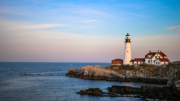 Rocky Maine coastline with a lighthouse in the distance