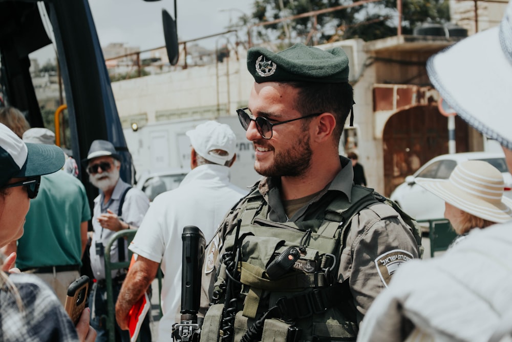 Hombre sonriente con uniforme de soldado de pie cerca de la multitud durante el día