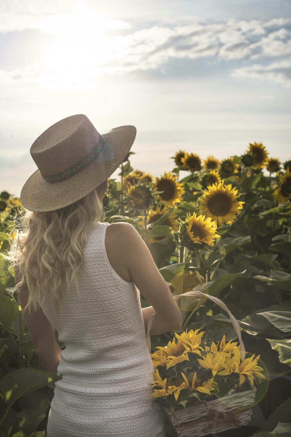 Mujer de pie sosteniendo la canasta frente de girasol