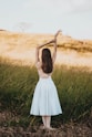 woman wearing white sleeveless dress standing near grass at daytime
