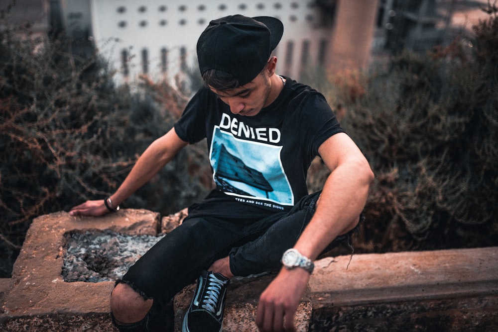 man sitting on rail near trees