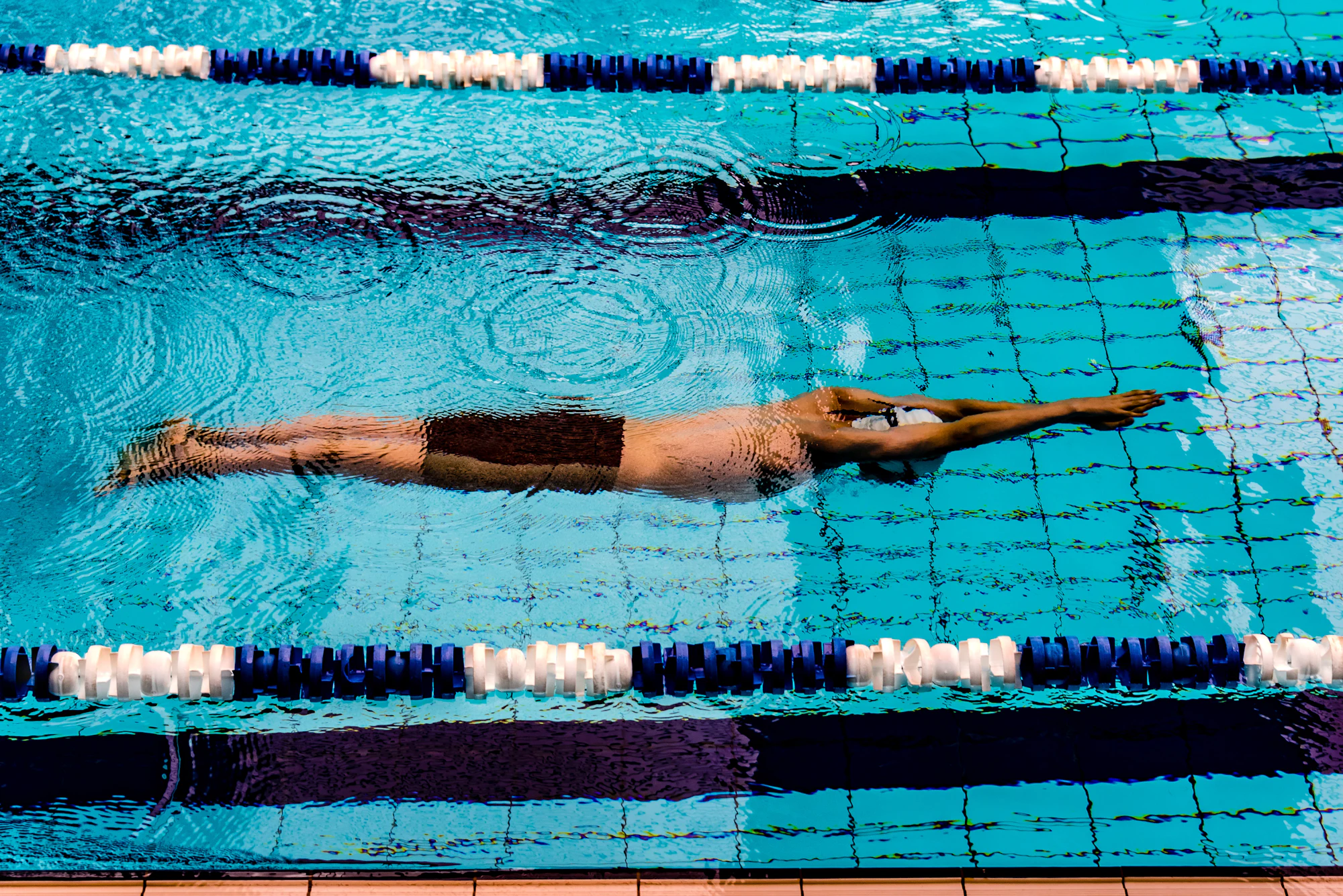 A swimmer streamlined in their lane, seen from above