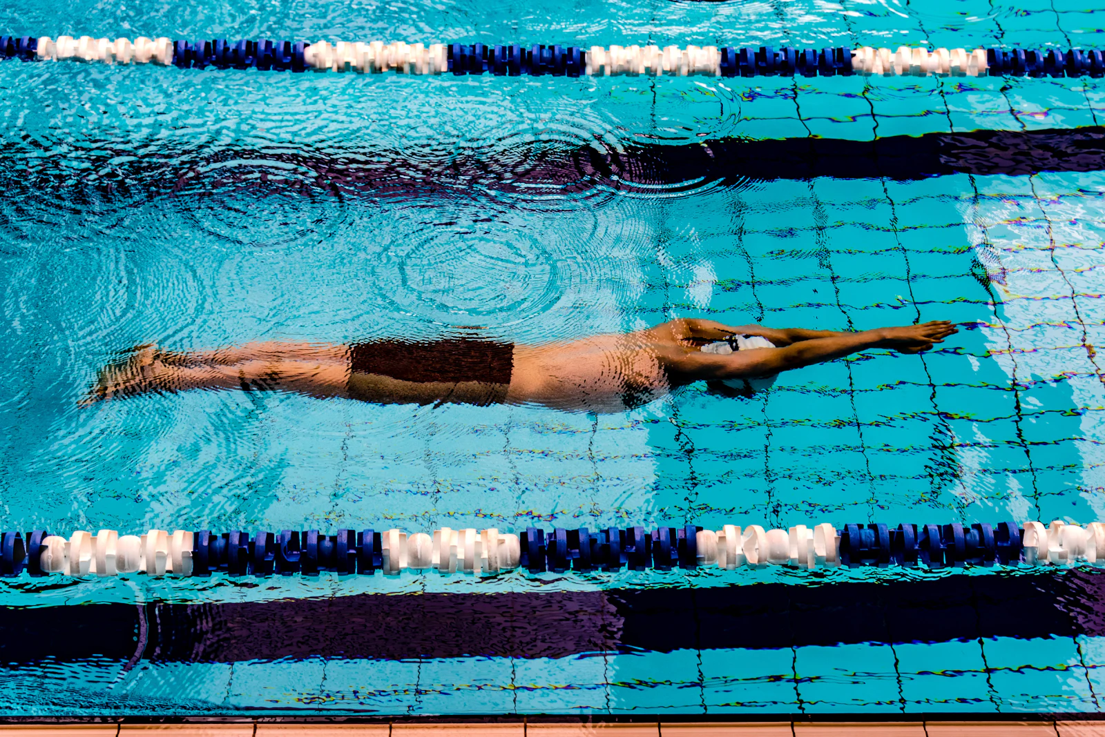 Nadador em nado crawl visto de cima na raia da piscina