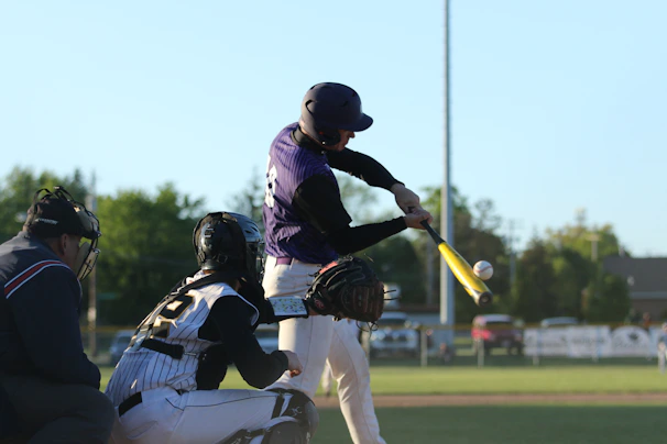 Close-up of a player in DMPL jersey mid-swing, ball soaring against a clear blue sky.