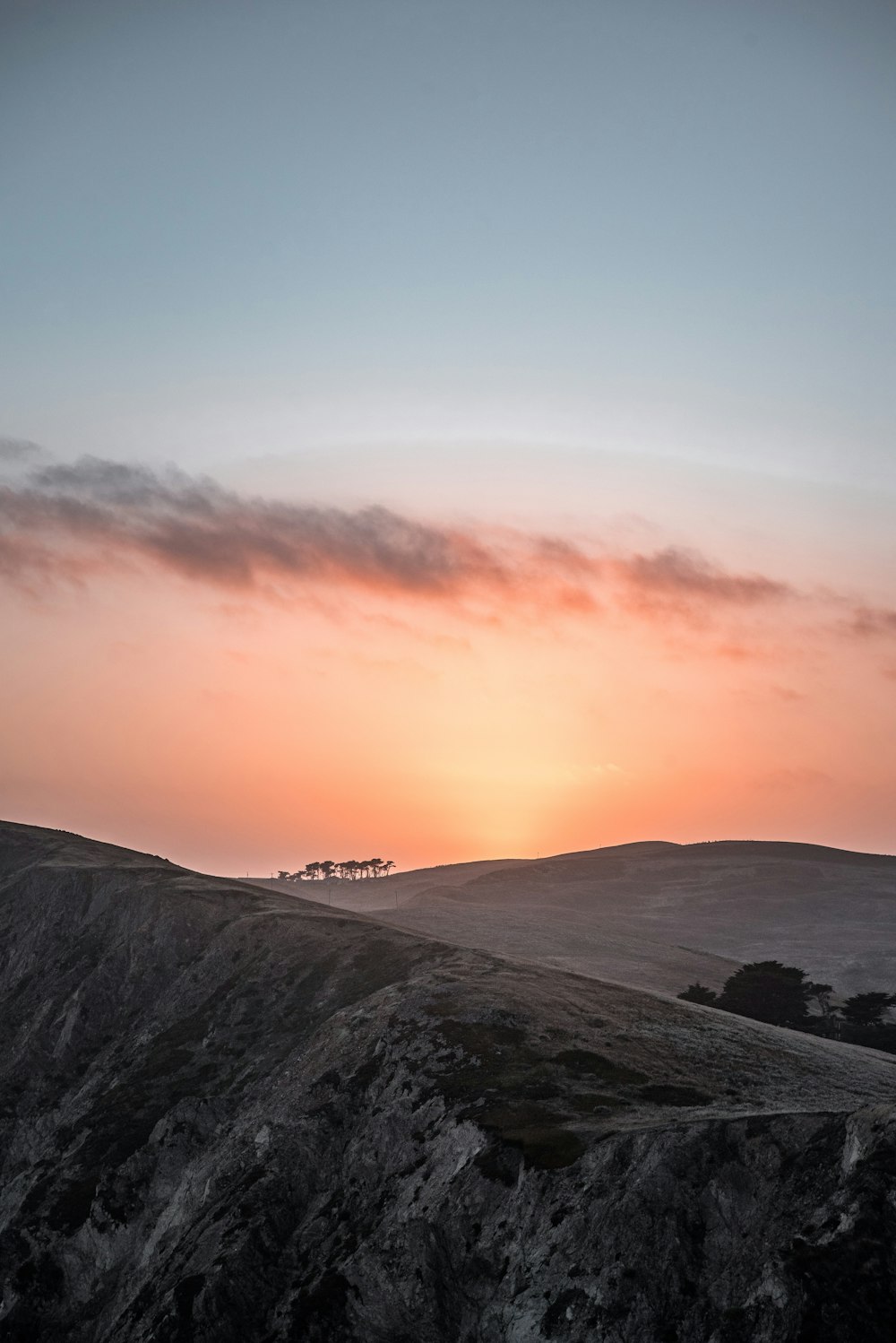 silhouette of leafed trees on mountain covered with snow during orange sunset