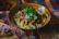A happy man savoring a vibrant Sinaloa-inspired pasta dish in a cozy restaurant setting.