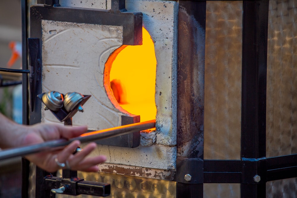 a person holding a metal object in front of a fire