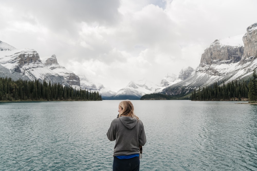 woman standing in front of lake and mountains
