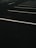 A dimly lit, empty parking lot with white painted lines marking parking spaces. The dark asphalt and overcast lighting create a sense of solitude.
