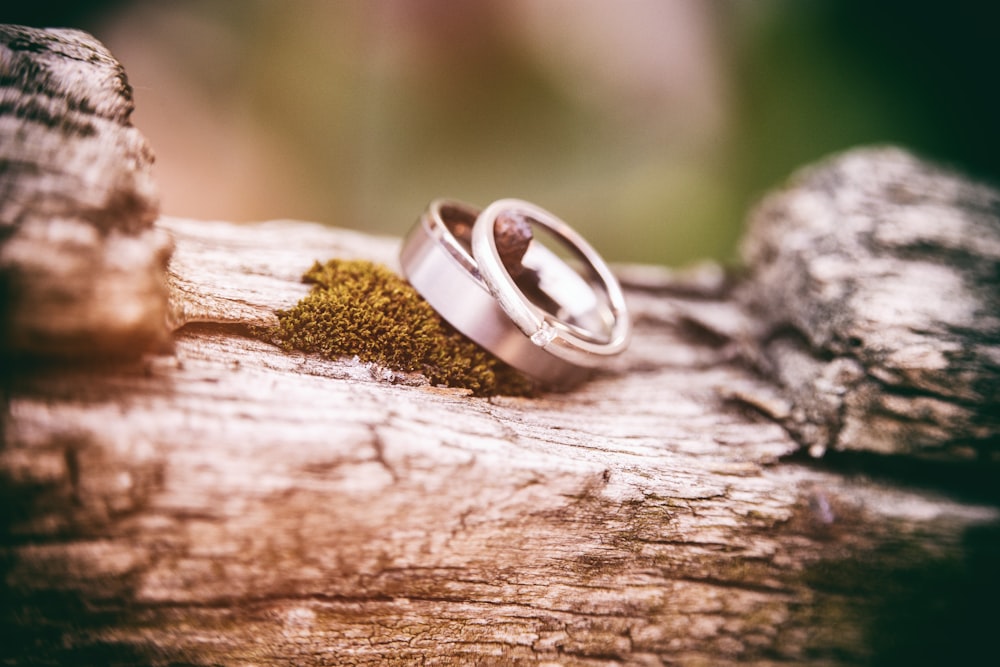 two silver-colored wedding bands on gray wood