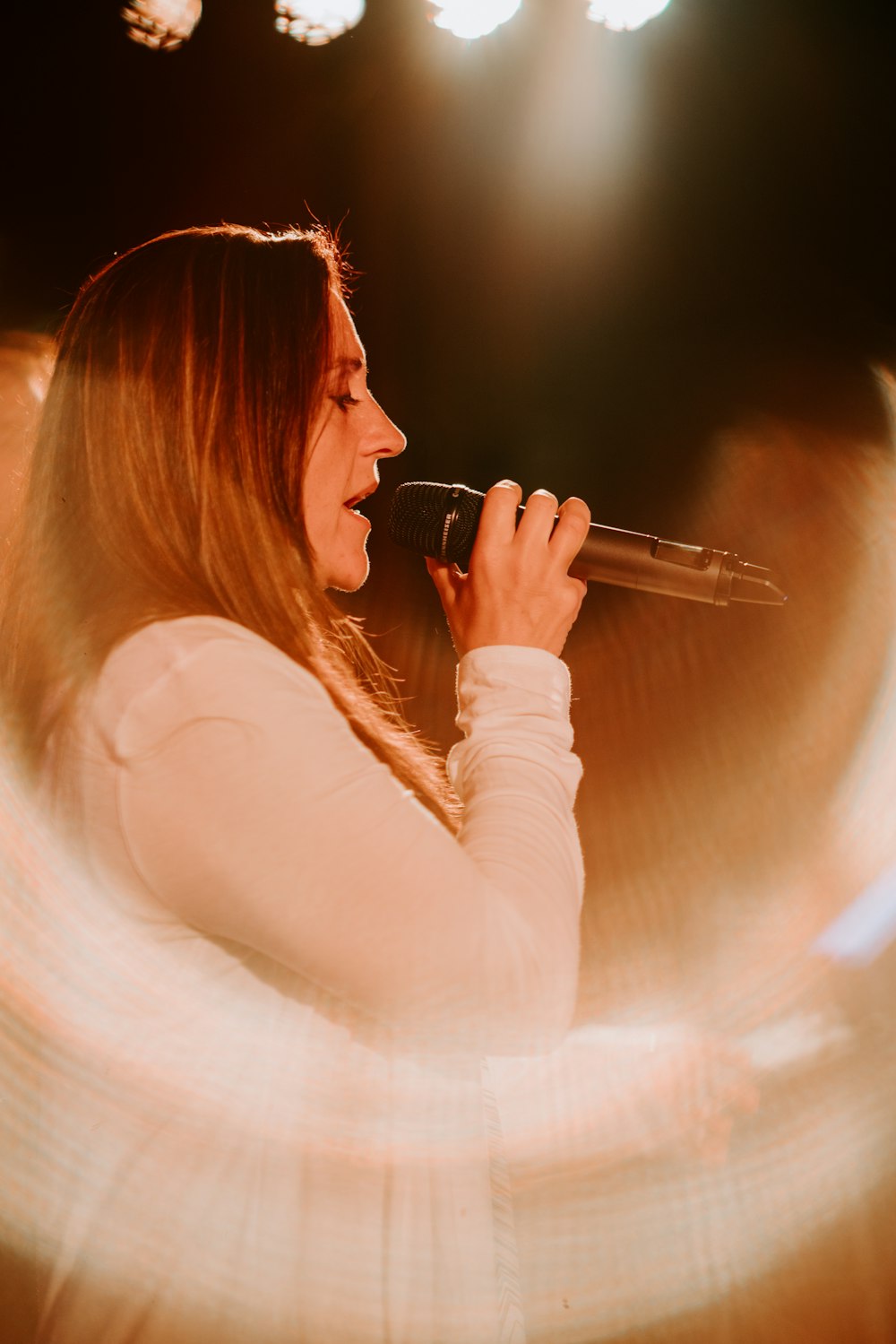 Frau hält Mikrofon in der Hand, während sie auf der Bühne singt