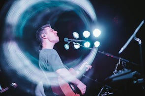 Photograph of a musician passionately playing an acoustic guitar on stage.
