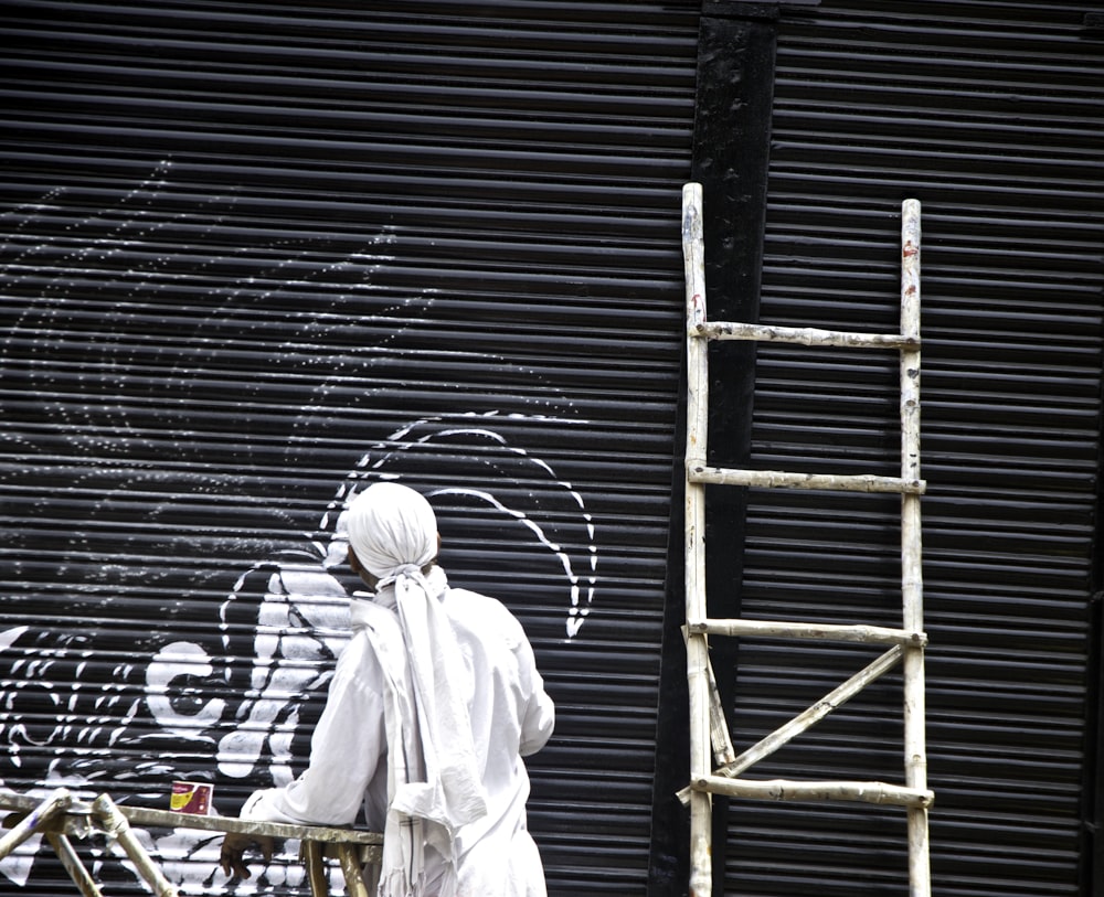 man standing beside brown wooden ladder