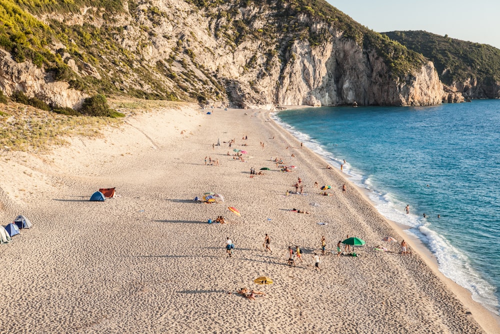 person on seashore near mountain at daytime