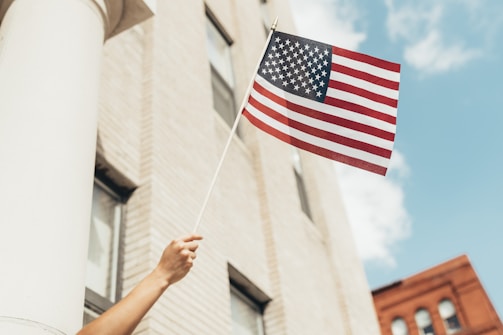 a person holding an american flag in front of a building