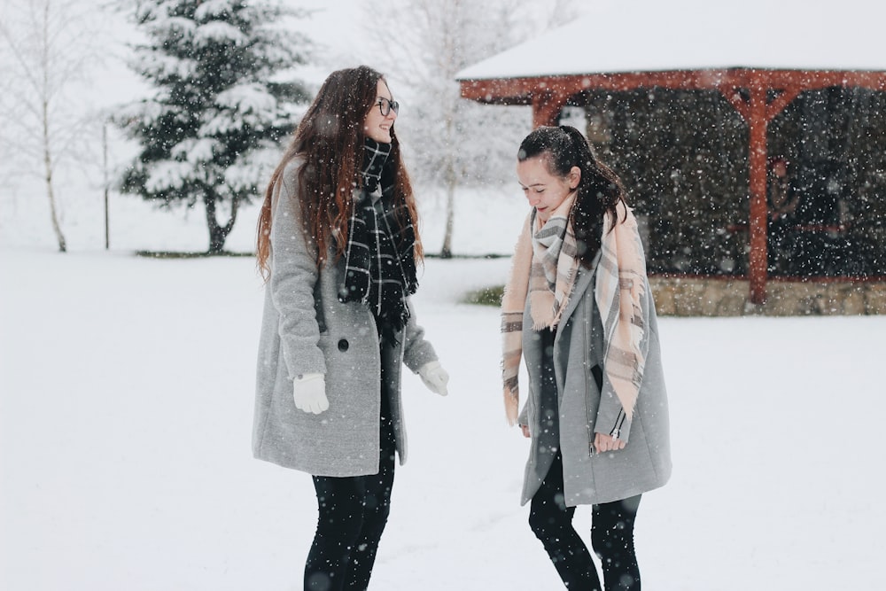 two woman standing on snow field