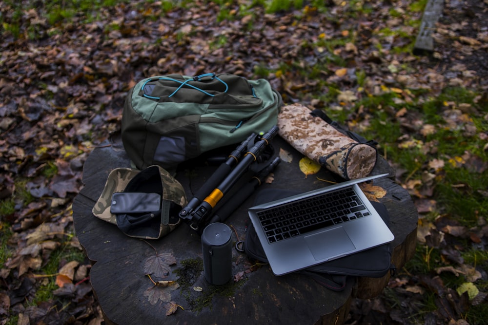 silver laptop, bag, and tripod at stump