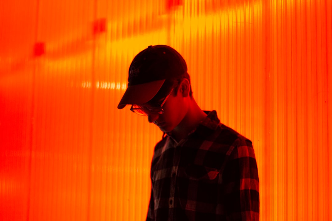 person wearing cap standing on orange wall