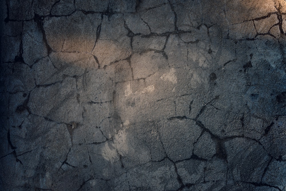 a cracked concrete wall with a light shining on it