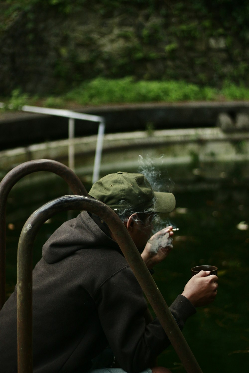 コーヒーを飲みながらレールの間で喫煙している男