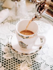 person pouring tea in white ceramic mug
