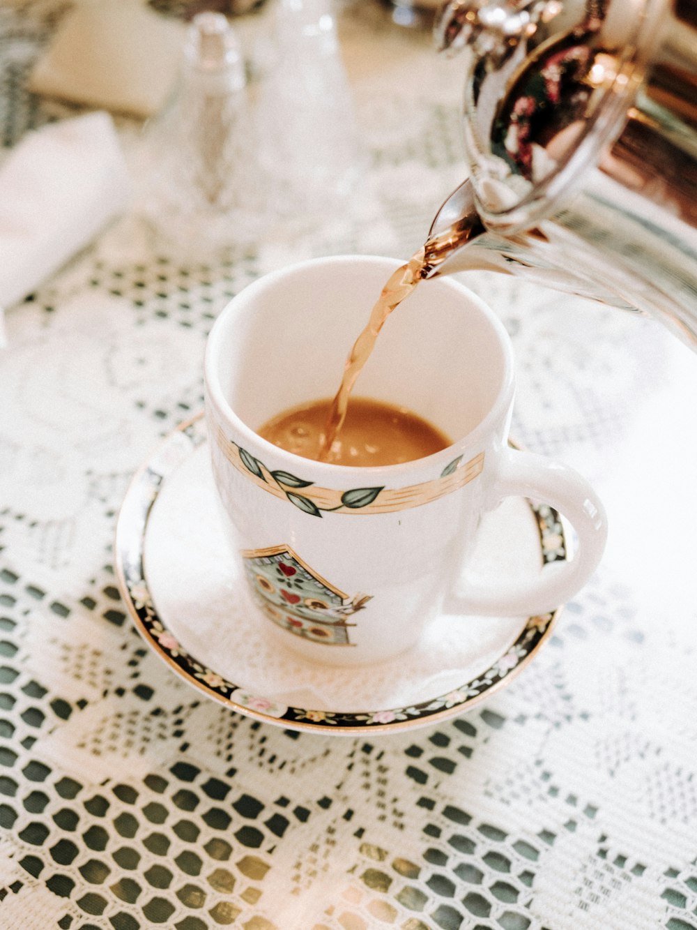 person pouring tea in white ceramic mug