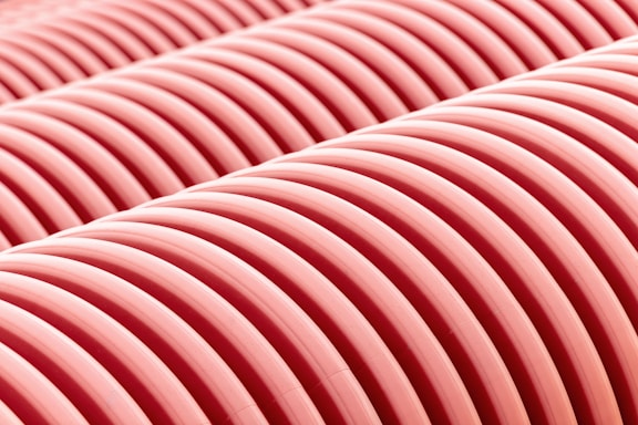 Rows of corrugated pink tubes aligned closely together, creating a pattern of parallel curved lines.