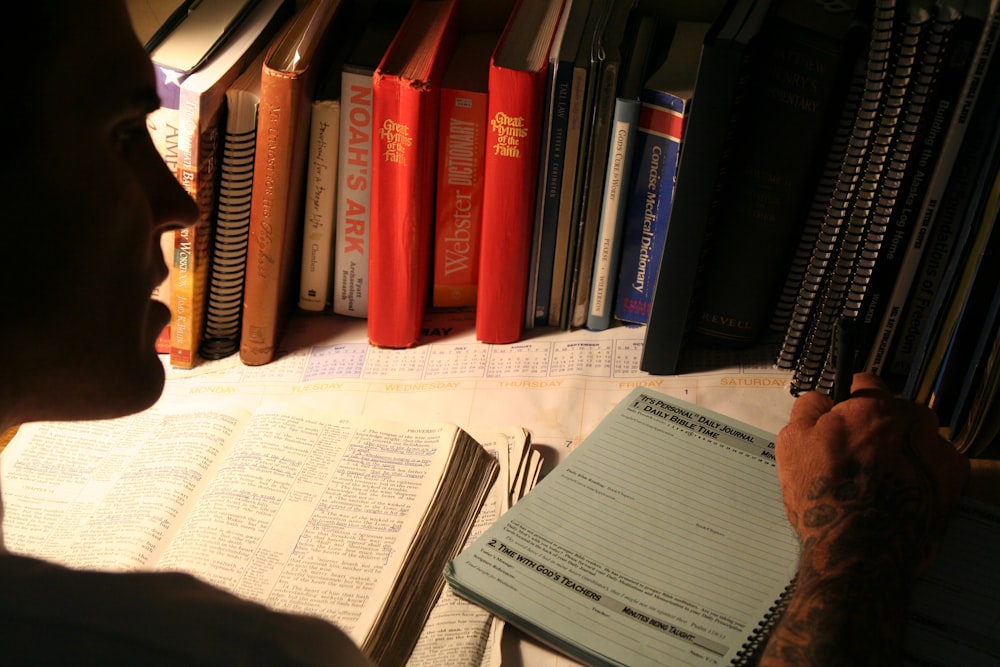 man writing in front of books