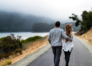 man and woman walking on asphalt road