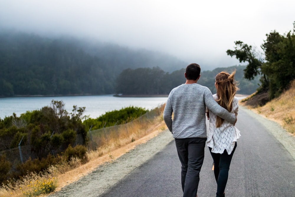 man and woman walking on asphalt road