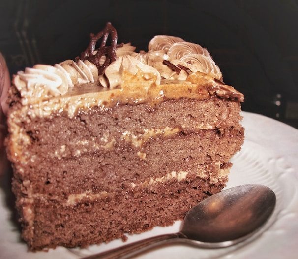 A slice of rich chocolate cake with creamy frosting on a rustic plate