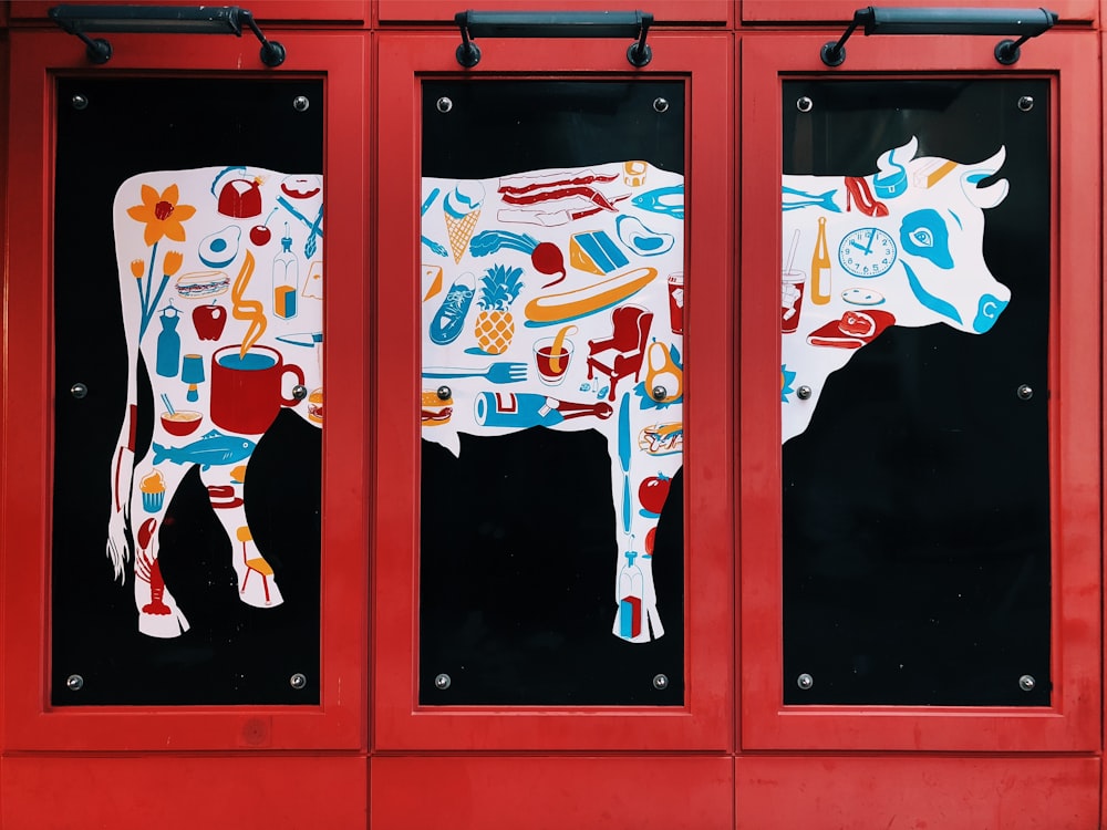 white, blue, and red cow 3-panel painting on wall