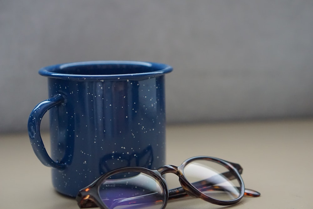 black metal mug beside eyeglasses