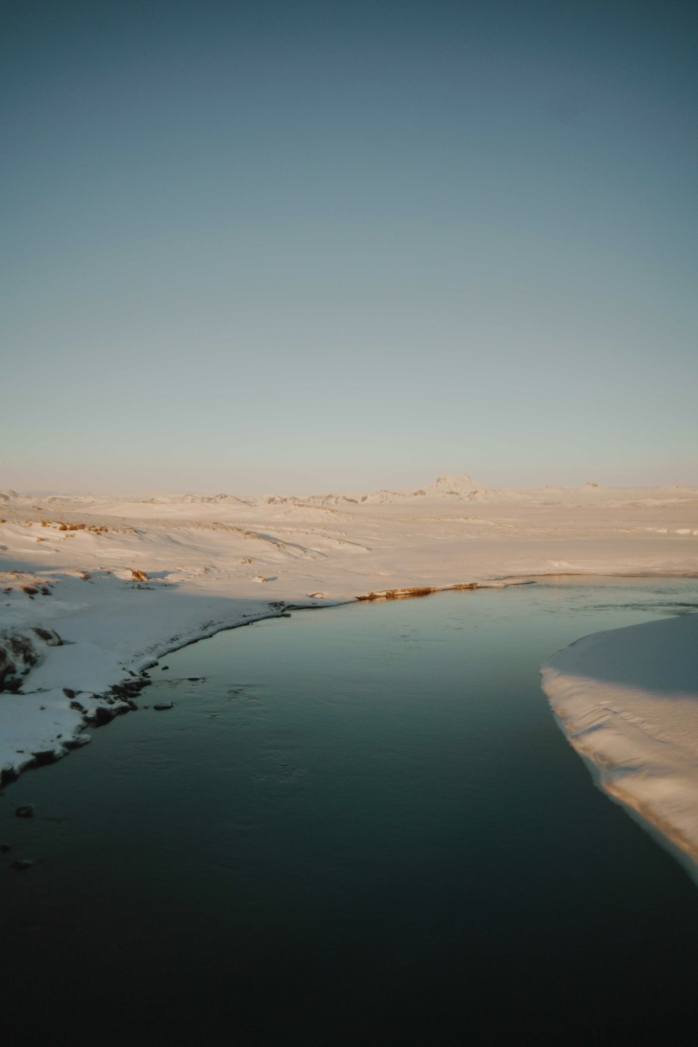 body of water surrounded by snowfield