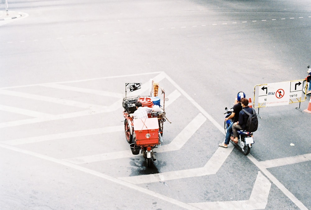 two motorcycles traveling on a black asphalt road