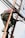 A person is climbing a ladder while working on electrical or communication cables. They are wearing work boots and protective gear, including knee pads, and have a harness for safety. Various cables are intertwined around the ladder.