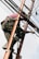 A person is climbing a ladder while working on electrical or communication cables. They are wearing work boots and protective gear, including knee pads, and have a harness for safety. Various cables are intertwined around the ladder.